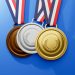 Três medalhas penduradas sobre um fundo azul: uma medalha de bronze à esquerda, uma medalha de prata no meio e uma medalha de ouro à direita. Cada medalha dos Jogos Olímpicos apresenta um desenho de coroa de louros e é presa a uma fita listrada de vermelho, branco e azul. | YogaLounge