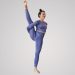 Uma pessoa em uma roupa de yoga roxa faz uma pose de split em pé contra um fundo claro simples. Ela fica em pé sobre uma perna com a outra perna estendida para cima, segurando a perna levantada com uma mão. Ela tem uma expressão serena e seu cabelo está preso, incorporando 20 anos de experiência e confiança como referência em formação de professores de yoga. | YogaLounge
