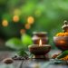 Uma vela quente tremula sobre uma mesa de madeira cercada por uma tigela com flores de calêndula, folhas, ervas e pequenos potes, criando um ambiente inspirado no Ayurveda contra um fundo verde suavemente desfocado. | YogaLounge