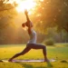 Uma pessoa decide praticar ioga no verão em um tapete em um parque ao nascer do sol, fazendo uma pose de lunge com os braços levantados, cercada por grama verde e árvores, enquanto a luz do sol atravessa o fundo. | YogaLounge